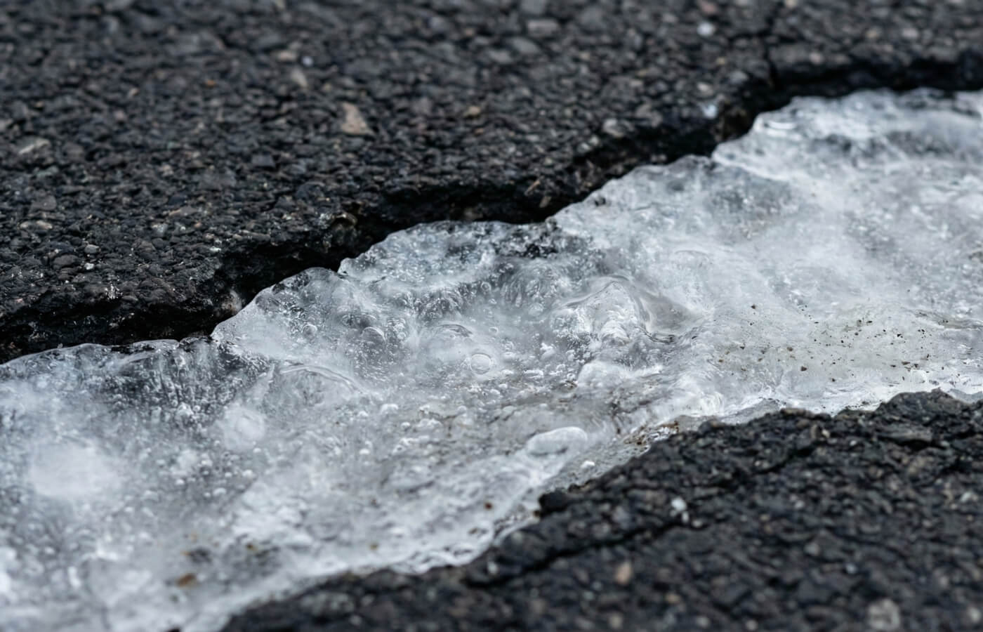 ice expanding in a pavement crack causing Ontario winter asphalt damage